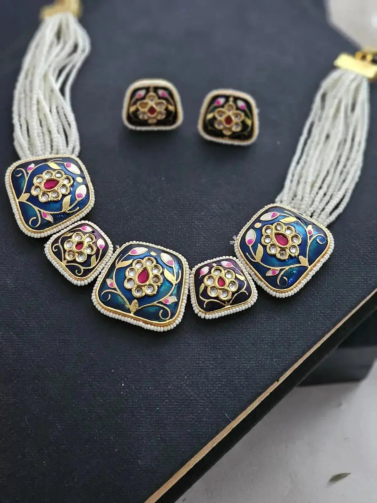 close up look Meenakari choker set with intricate enamel work with midnight blue and pink with gold.