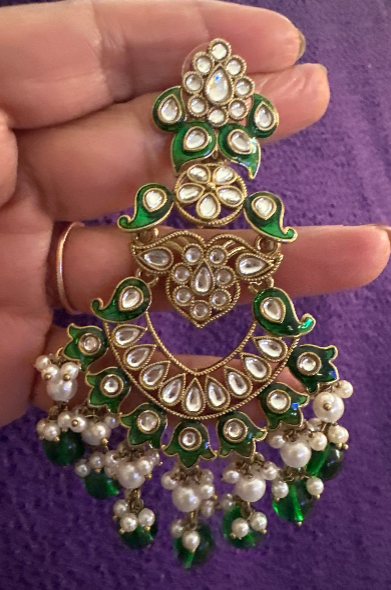 Green meenakari kundan chandbali earring held in hand showing floral stud top with green enamel petals, heart-shaped crescent body with teardrop polki-look stones and pearl cluster with green bead drops