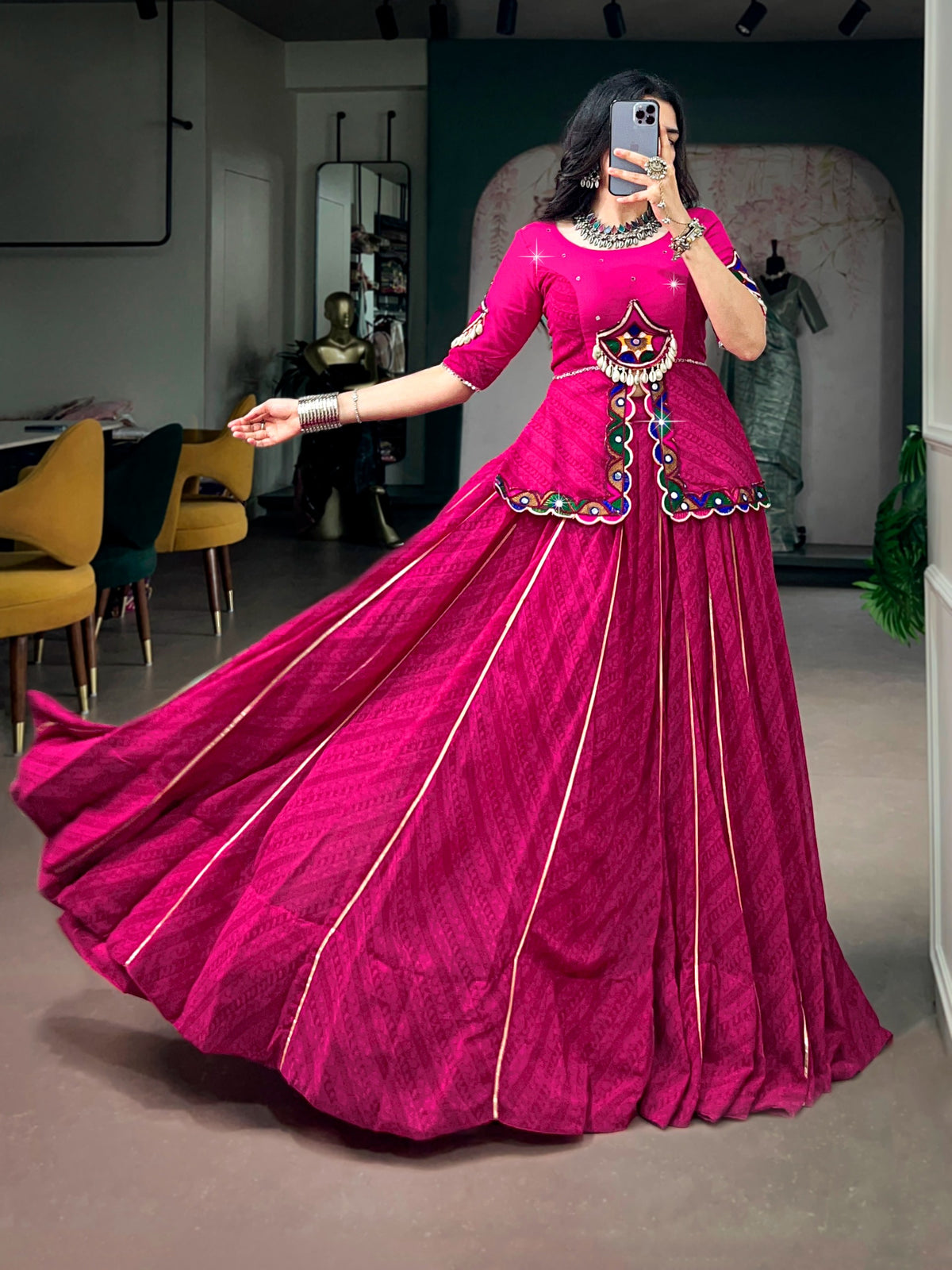 Model wearing rani pink lehenga choli set, twirling to show 8-metre flare with gold Gota Patti lace stripes and Kutchi peplum blouse