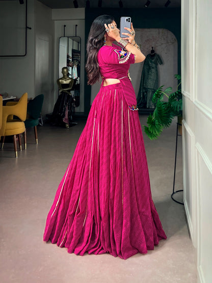 Side view of model in rani pink lehenga choli showing lace-up back closure on peplum blouse and full lehenga flare