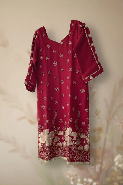 Red dress with white floral patterns on a hanger against a white wall.