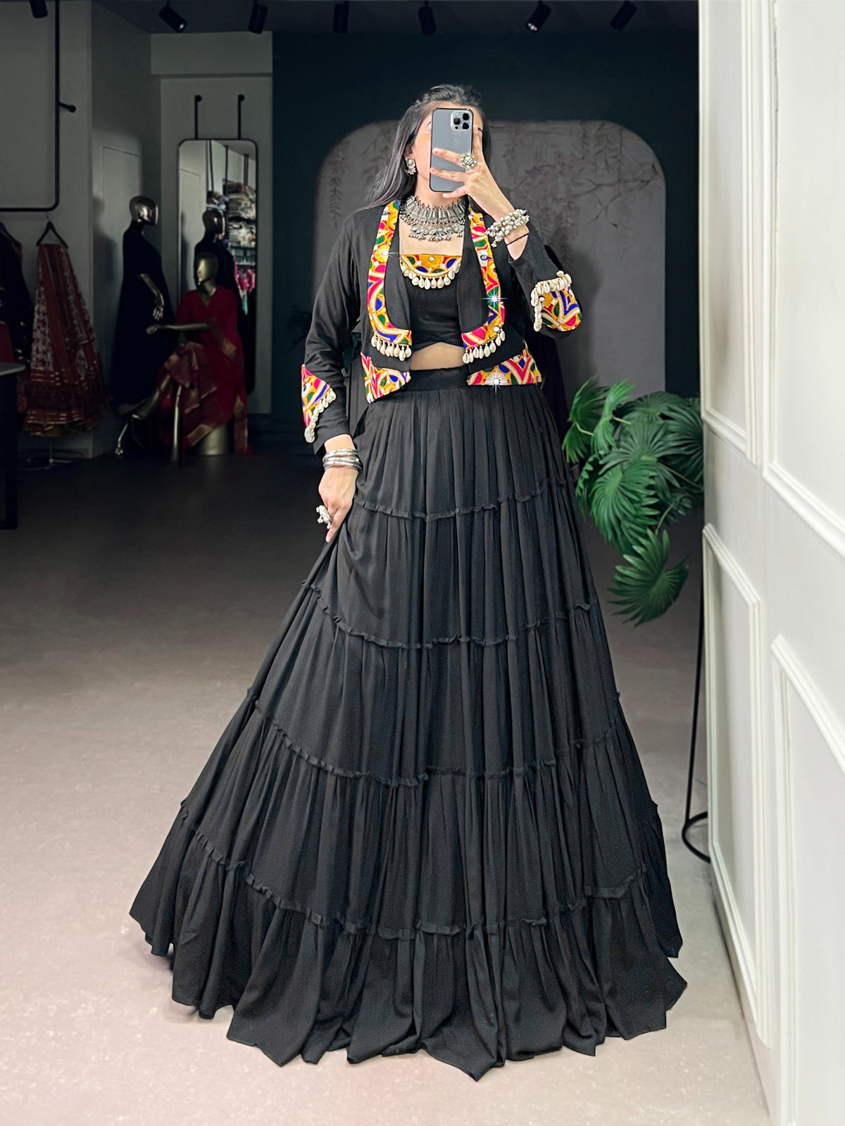 Model wearing rani pink Rajudi Chaniya Choli set with open-front Kutchi jacket featuring Gamthi embroidery, cowrie shell tassels and tiered flared chaniya
