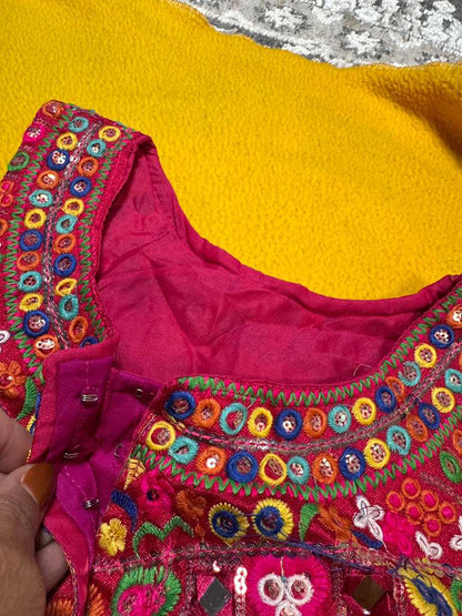 Close-up of magenta Kutchi halter blouse neckline showing hook closure and multicolour Rabari embroidery detail