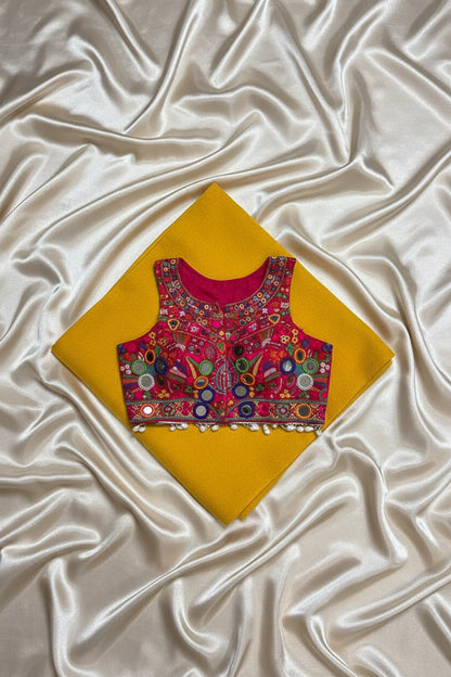 Back view of magenta Kutchi halter crop blouse showing cowrie shell fringe and mirror work detail