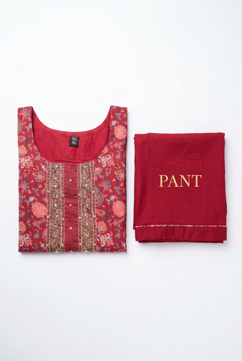 Folded cranberry-red floral kurta and coordinating solid red pants showing neckline handwork