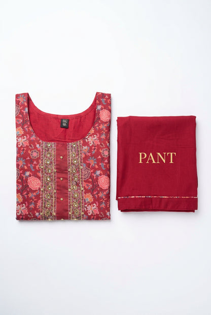 Folded cranberry-red floral kurta and coordinating solid red pants showing neckline handwork